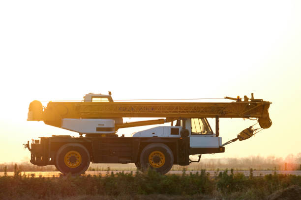 Heavy duty mobile lifting crane driving on intercity road at sunset Heavy duty mobile lifting crane driving on intercity road at sunset. industrial music stock pictures, royalty-free photos & images