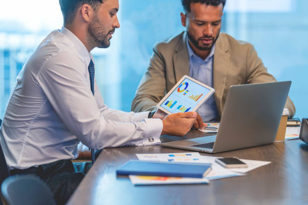 istock Business men working on financial data, graphs and charts on a digital tablet. 1406998232