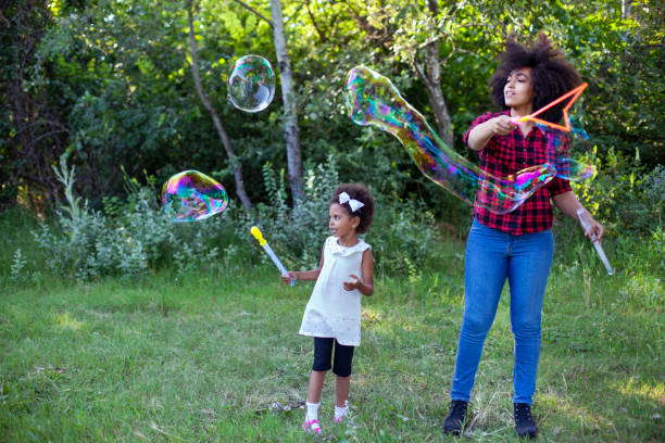 istock Happy mother and her daughter playing soap bubbles in park. 1406998258
