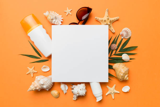istock Summer time concept with blank greeting card and blank white paper on colored background. Seashells from ocean shore in the shape of frame separated with space for text top view 1407001421