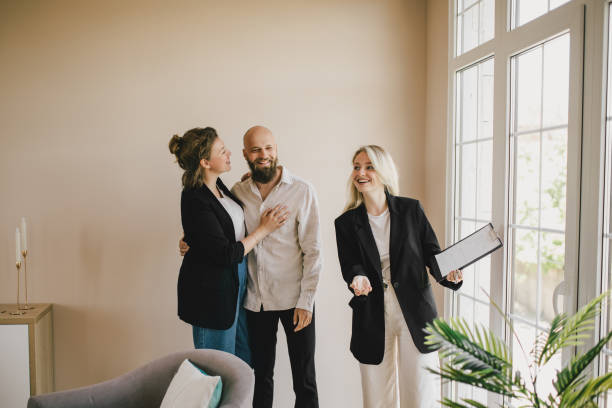 agente imobiliário demonstrando um novo apartamento para um casal feliz. - corretor de imóveis - fotografias e filmes do acervo