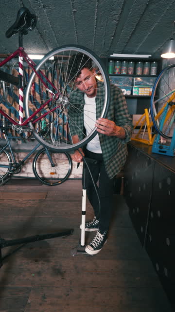 Male mechanic inflating the rear wheel of the bicycle.