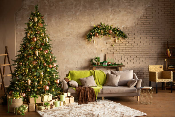 istock Modern Christmas living room interior in studio apartment. Large decorated Christmas tree, sofa, plaid, gift boxes, fluffy carpet, light garlands. Trending colors 2022: green, coffee, beige, khaki 1407020934