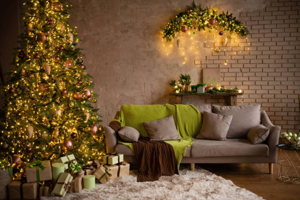 istock Modern Christmas living room interior in studio apartment. Large decorated Christmas tree, sofa, plaid, gift boxes, fluffy carpet, light garlands. Trending colors 2022: green, coffee, beige, khaki 1407021573