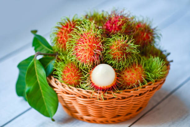 rambutan fresco e maturo rambutan dolce rambutan sbucciato con foglia, frutto di rambutan sul fondo del cesto raccolto dall'albero di rambutan del giardino - rambutan foto e immagini stock