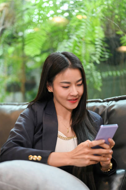 istock Charming Asian businesswoman sitting on sofa and using smartphone 1407024582