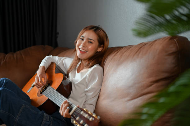 istock Attractive and talented millennial Asian girl playing guitar. Creative activity concept 1407024707