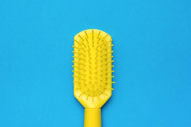istock Massage plastic yellow comb on a blue background. Minimal hair care concept. 1407028809