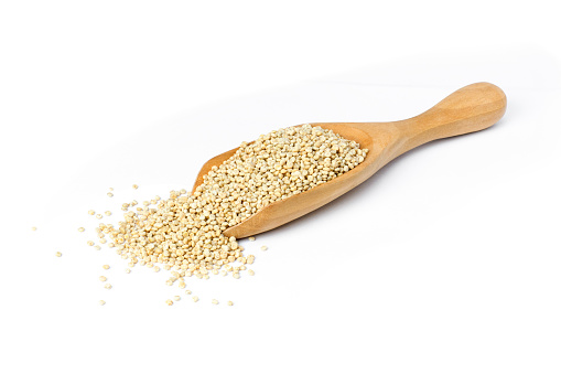 Quinoa seeds (Chenopodium) in wooden spoon isolated on white background.