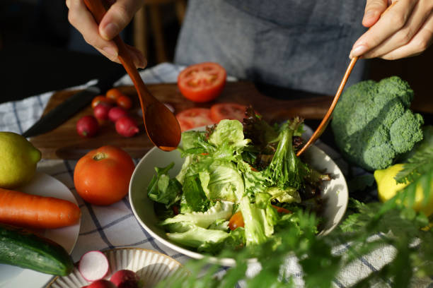 istock Woman tossing salad in domestic kitchen 1407032768