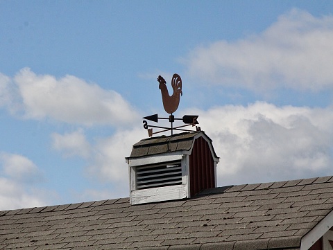 Rooster weather vane on top of a barn