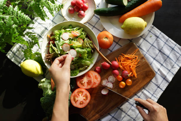 istock Female Hand putting fresh red radish into a bowl with different vegetables 1407034744