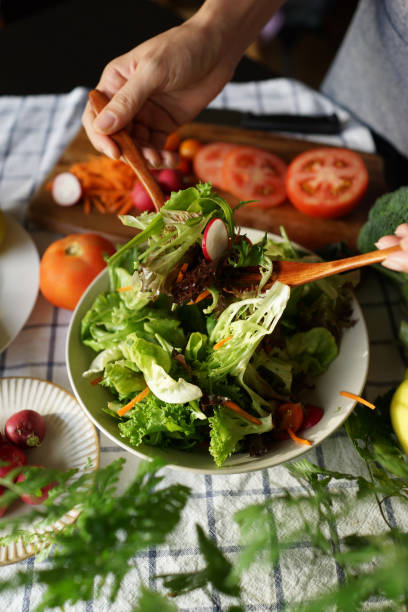 istock Woman tossing salad in domestic kitchen 1407034851