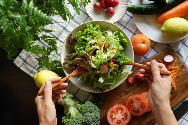 istock Woman tossing salad in domestic kitchen 1407035408
