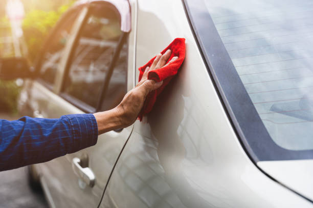 istock Man's hand cleaning car & drying vehicle with microfiber cloth. Hand wipe down paint surface of shiny blue sedan after polishing and ceramic coating. Car detailing, maintenance, and car wash concept. 1407035431