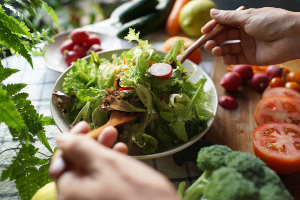 istock Woman tossing salad in domestic kitchen 1407035470
