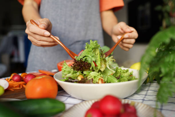 istock Woman tossing salad in domestic kitchen 1407035510