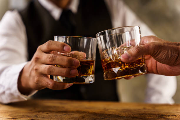 zwei hände klirren gläser whiskey wiskey auf der couch, gemütlich. bar-trinkkarte. - whisky stock-fotos und bilder