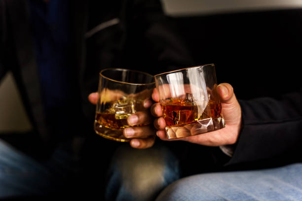 dwie ręce brzęczą szklanki whisky wiskey na kanapie, przytulne. menu do picia w barze. - clink zdjęcia i obrazy z banku zdjęć
