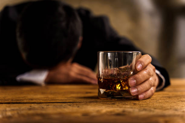 istock Alcoholism, depressed asian young man sleep on table while drinking alcoholic beverage, holding glass of whiskey alone at night. Treatment of alcohol addiction, suffer abuse problem alcoholism concept 1407035709