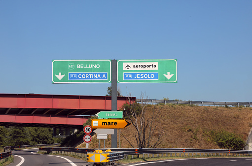 Crossroad on the italian highway and the indication to place Belluno Cortina JESOLO and Venice Airport and text MARE that means SEA in Italian language