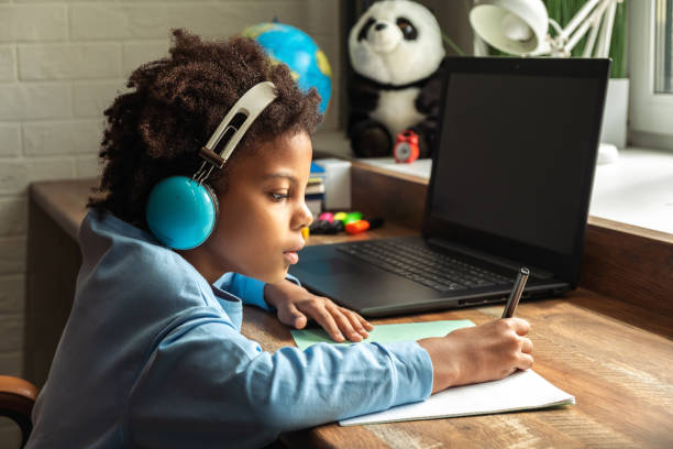 istock African-American girl doing homework,making notes,using headphones and laptop at home.Back to school concept.School distance education at home,home schooling,diverse people 1407038048