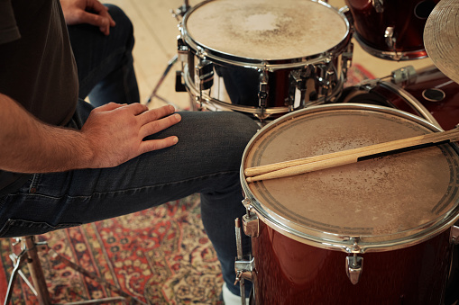 Close-up of drummer sitting at drums set and resting after his performance