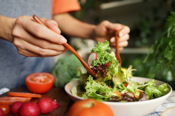 istock Woman tossing salad in domestic kitchen 1407039365