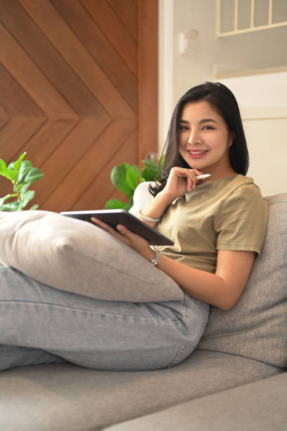 istock Pretty young woman resting on comfortable sofa and using digital tablet. 1407042471