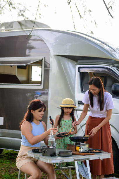 szczęśliwa wielopokoleniowa azjatycka rodzina gotująca jedzenie podczas pikniku przy przyczepie kempingowej na plaży - class a motorhome zdjęcia i obrazy z banku zdjęć