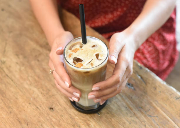 istock Woman's hands  holding a glass of ice coffee 1407045134