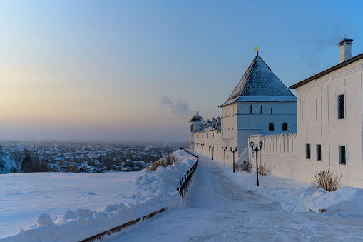 On a frosty winter morning, a view of the city of Tobolsk (Russia), lying under a mountain and one of the old towers of the Kremlin. Light fog from a heavy night frost, smoke from chimneys, snowdrifts