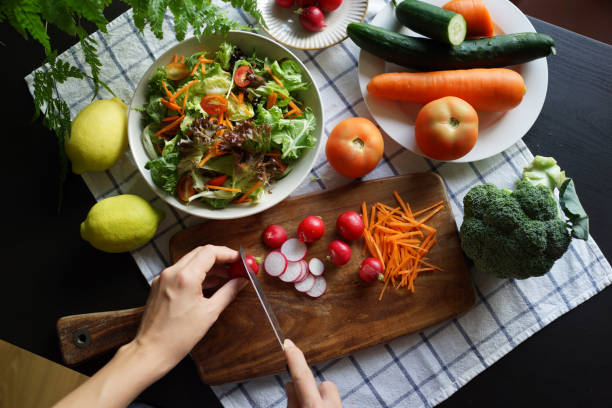 istock Close up female hand preparing vegetarian salad, top view 1407048065