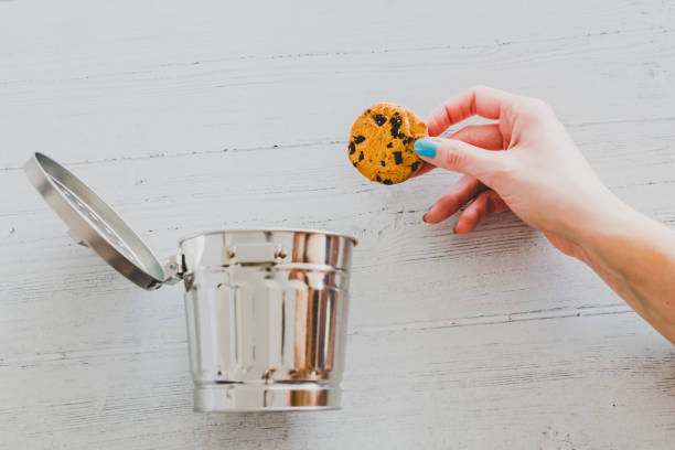 hand throwing website cookie going into a trash can stock photo