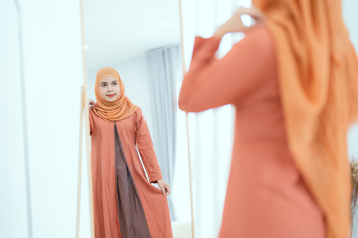 Muslim woman happily dressed in front of the mirror in the morning in the bedroom.