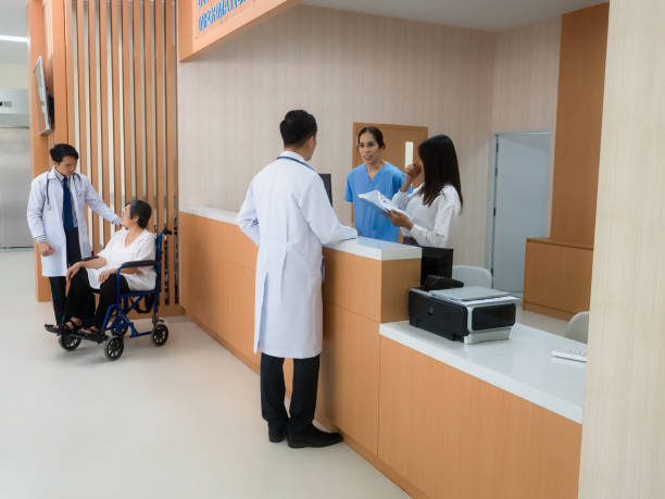 Administrative information counter at hospital At hospital information counter doctor speaking to administraive crew, another doct talking with patient on wheel chair speaking with forked tongue stock pictures, royalty-free photos & images