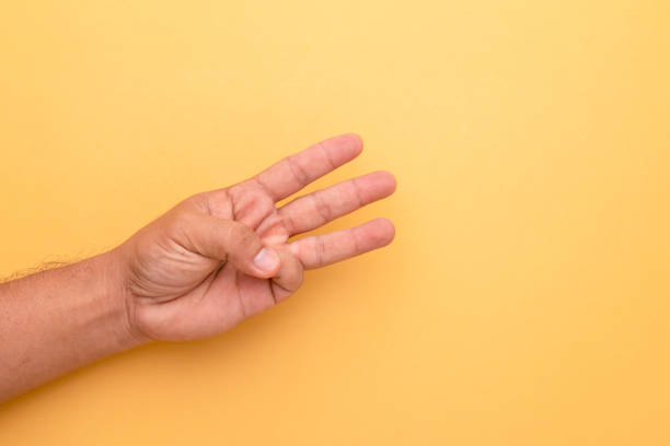 istock Hand showing three finger symbol on orange background with copy space 1407060493