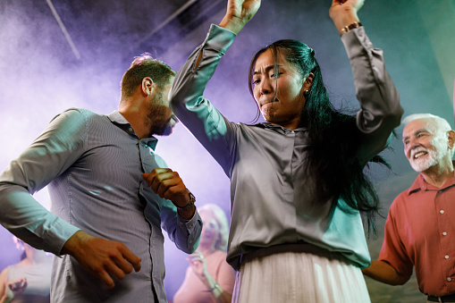 Low angle view of carefree woman having fun while disco dancing during nightlife in a club.