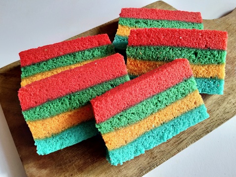 Some slice of steamed rainbow cake on wooden cutting board