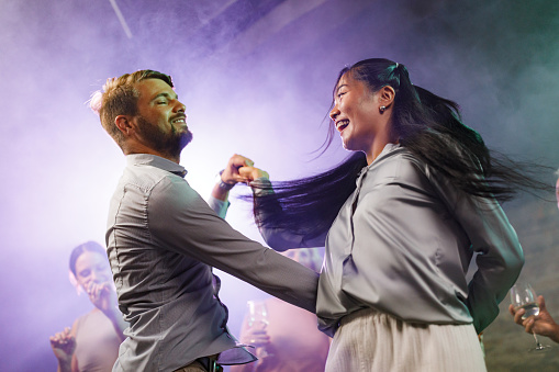 Happy couple having fun while disco dancing during nightlife in a club.