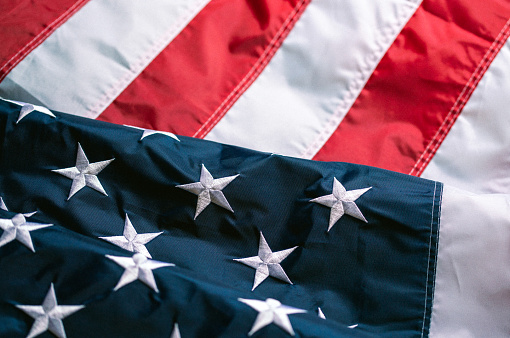 Waving big flag of United States of America on blue sky background