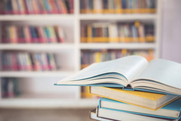 istock Book stack on the table in the library room and blurred space of bookshelf background 1407064002