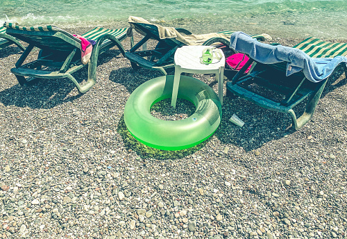 vacation by the sea on the beach. on the ground are swimming accessories, diving goggles, a light green rubber life buoy for a child.