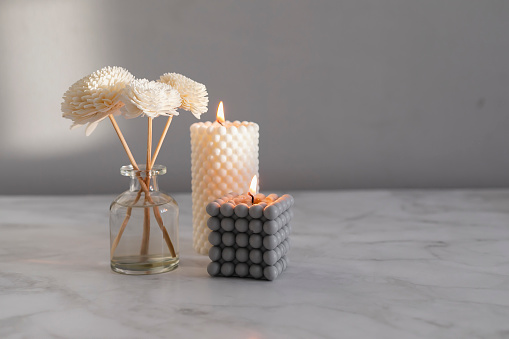 Home aroma fragrance diffuser and burning candles on marble background. Interior elements. Home aroma. Wellness