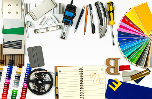 Outdoor advertising agency tools, accessories and material samples. Palette of film colours, aluminium profile and plastic samples and instruments on the white background. Top view. No people. Isolated