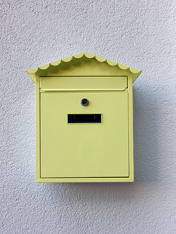 Yellow mailbox hanging on the white wall