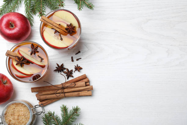 istock Hot mulled cider, ingredients and fir branches on white wooden table, flat lay. Space for text 1407066910