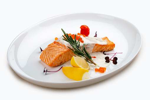 Salmon fillet with sauce and red caviar, rosemary and lemon.