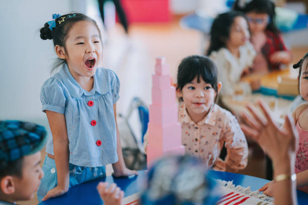 Happy Asian chinese Montessori Preschool students with their achievement building tower with toy block Happy Asian chinese Montessori Preschool students with their achievement building tower with toy block asian kindergarten stock pictures, royalty-free photos & images