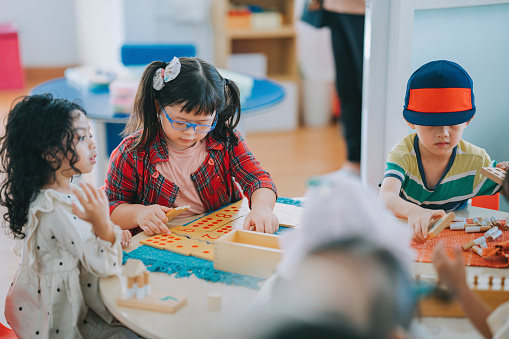 asian Montessori preschool students playing arranging toy block in classroom